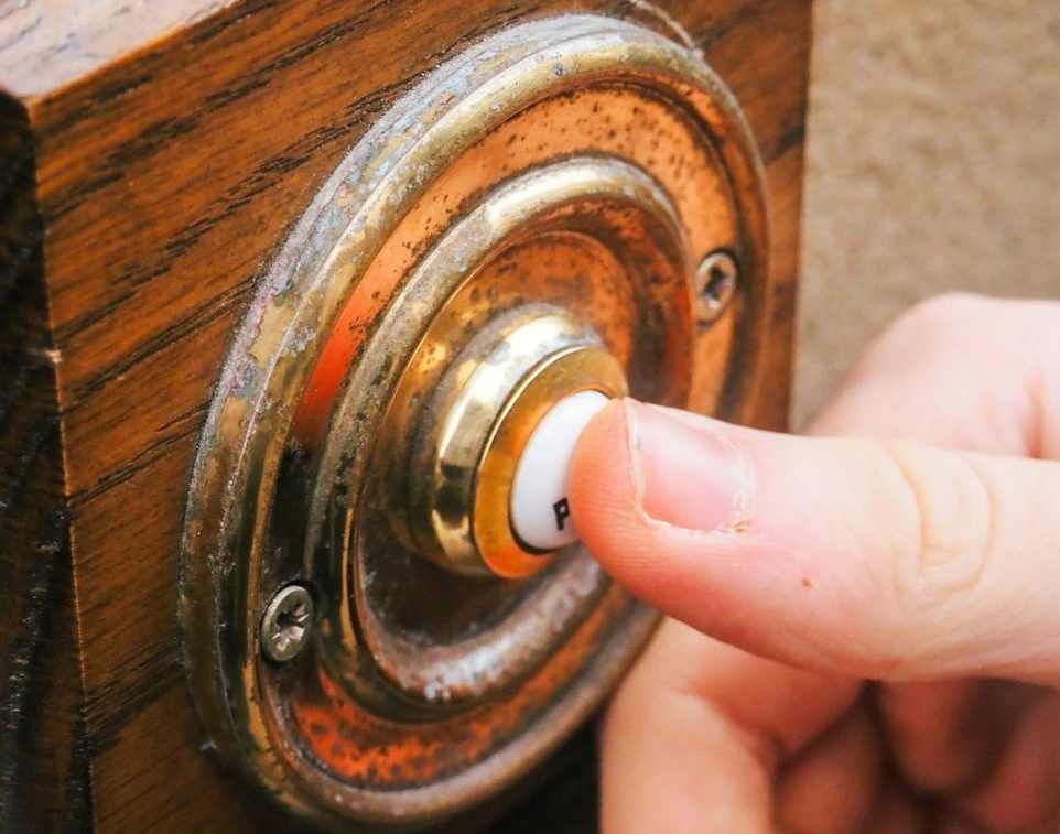 a person pressing a button on a wooden door